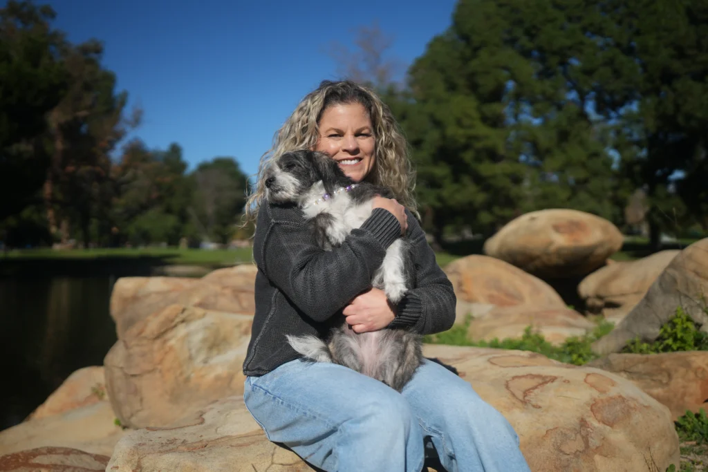 Fullerton therapist Keri Prather, LMFT, smiling outdoors with her small therapy companion, Piper.